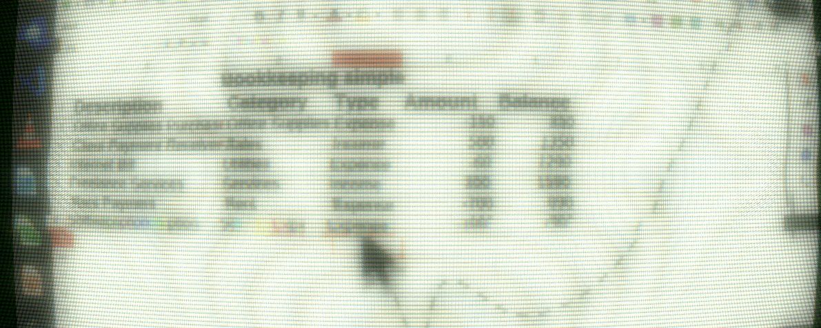 Close-up of a cursor over a blurred computer desktop interface, photographed through the screen pixels